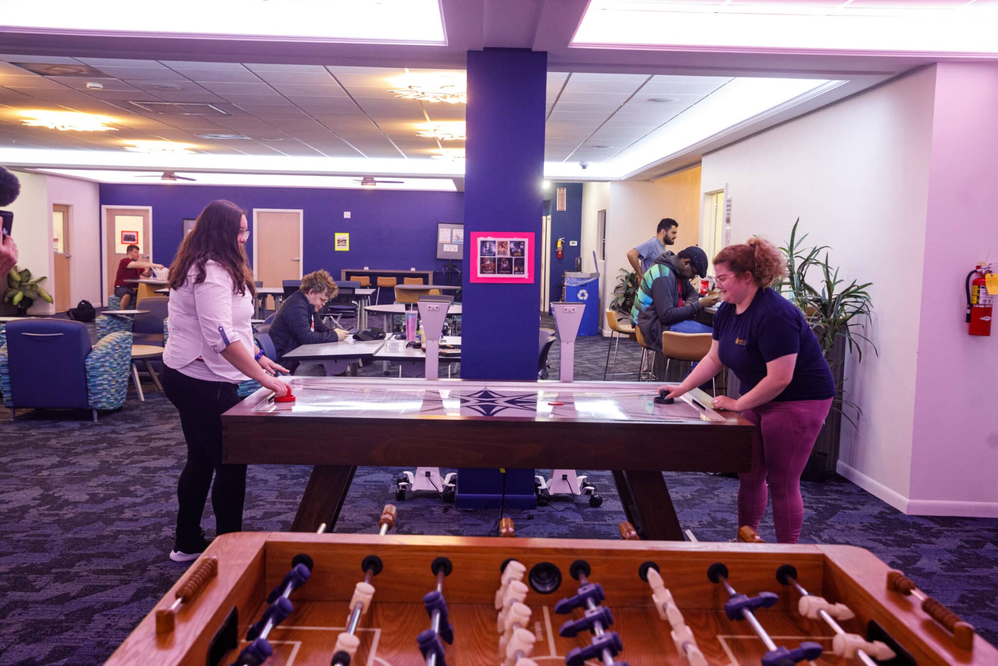 Two female students playing air hockey in the Student Center.