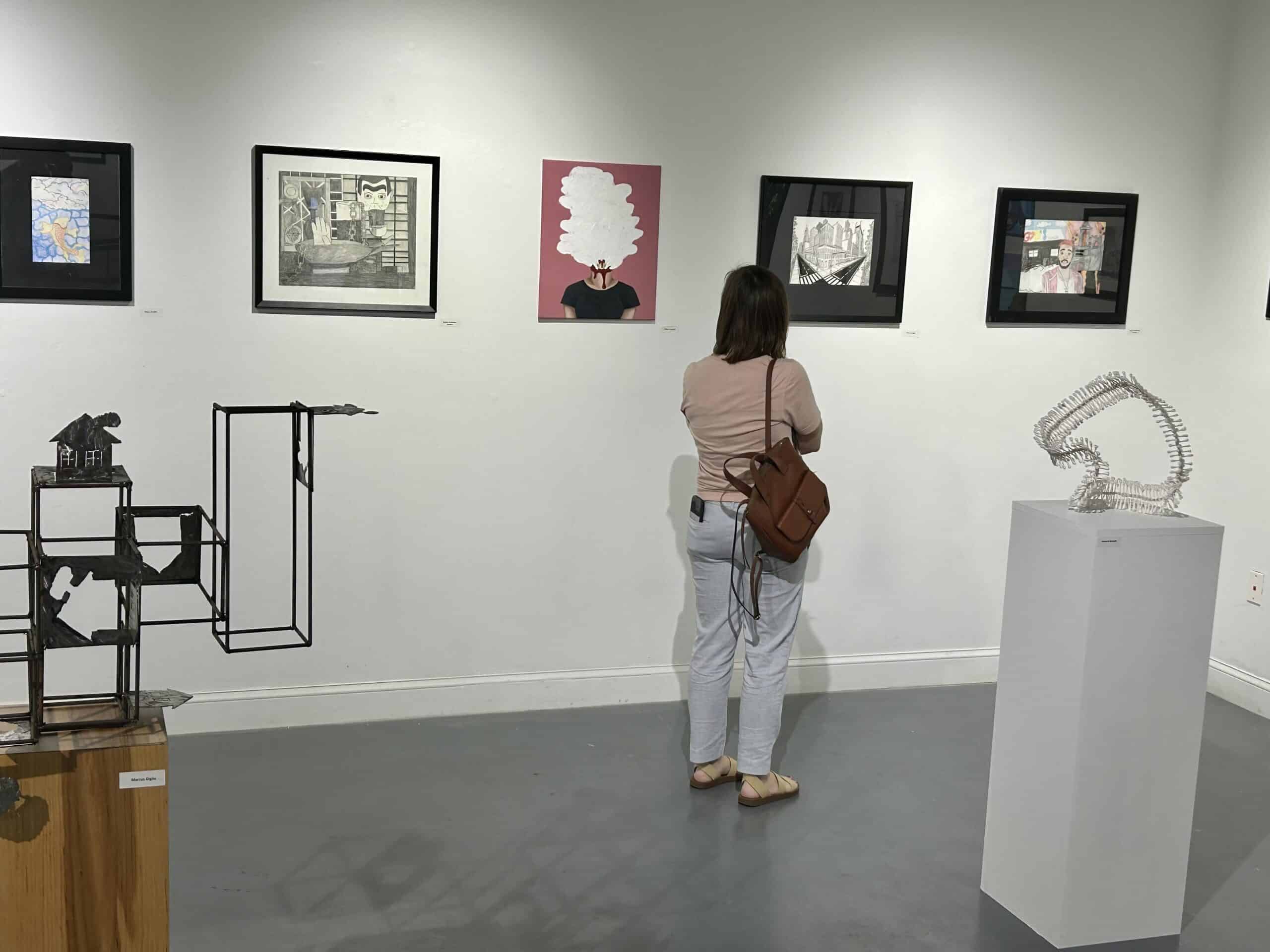 woman viewing student art in gallery