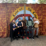 Dungeons and Dragons club members standing in front of Renaissance Faire sign